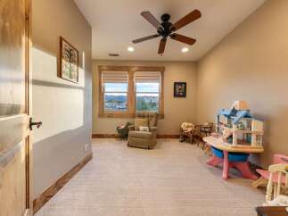 This charming room is perfect for children, featuring a dollhouse, toy table, and comfortable seating.