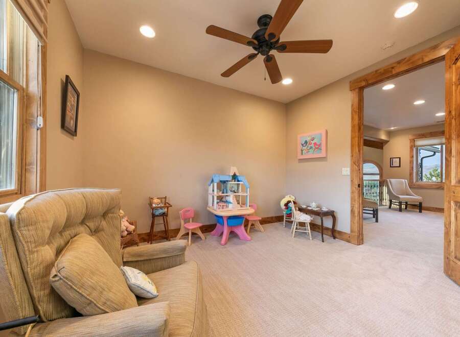 This charming room is perfect for children, featuring a delightful dollhouse, a miniature tea set, and a cozy armchair for relaxation.