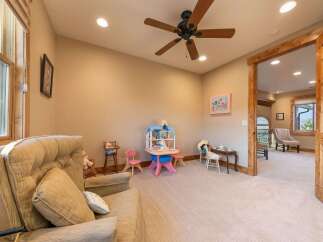 This charming room is perfect for children, featuring a delightful dollhouse, a miniature tea set, and a cozy armchair for relaxation.