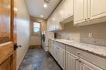 This spacious laundry room features a large sink, ample cabinet storage, and a granite countertop perfect for folding clothes.