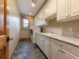 This spacious laundry room features a large sink, ample cabinet storage, and a granite countertop perfect for folding clothes.