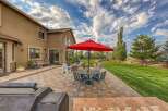 Enjoy outdoor living at its finest with this spacious patio featuring a dining set under a vibrant red umbrella, perfect for al fresco meals.