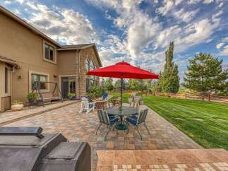 Enjoy outdoor living at its finest with this spacious patio featuring a dining set under a vibrant red umbrella, perfect for al fresco meals.