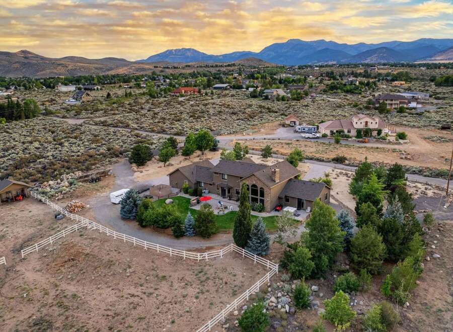 Experience luxury living in this expansive estate, featuring a stunning main residence with a grand stone fireplace and large windows offering breathtaking mountain views.