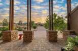 Experience breathtaking sunsets from this stunning property, framed by rustic stone pillars and a charming paver walkway leading to a magnificent home.