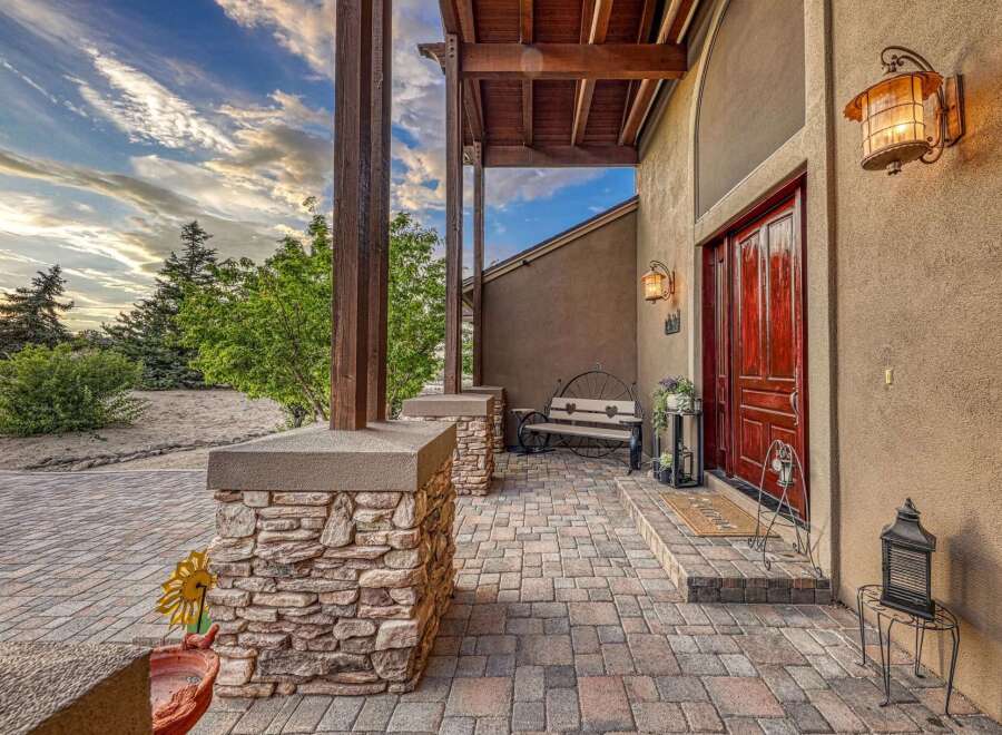 Welcome guests to this stunning property with a charming stone-accented porch and a grand wooden front door.