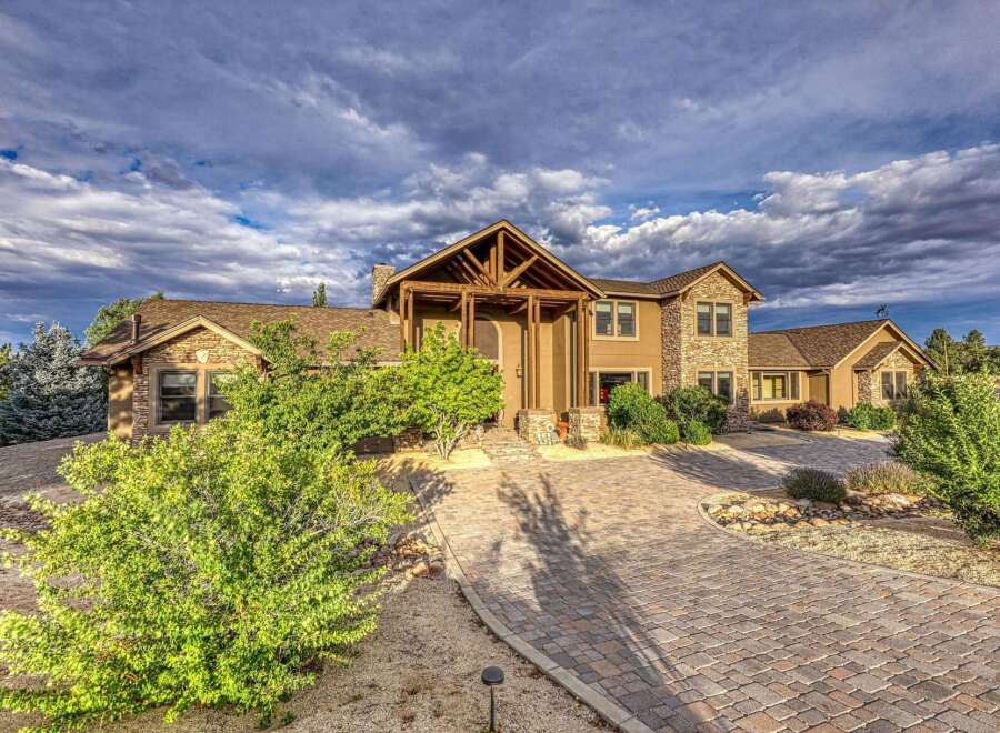 Discover this stunning luxury home featuring a grand entrance with a covered wooden porch and stone accents.