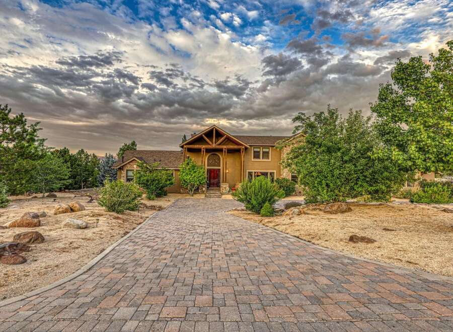 Discover this stunning estate featuring a grand entrance with a rustic wooden archway and a vibrant red door, leading to a spacious home.