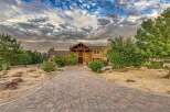 Discover this stunning estate featuring a grand entrance with a rustic wooden archway and a vibrant red door, leading to a spacious home.