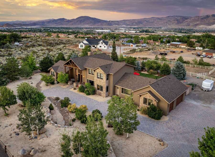 Experience luxury living in this stunning estate, featuring a grand entrance with a covered porch and stone accents.