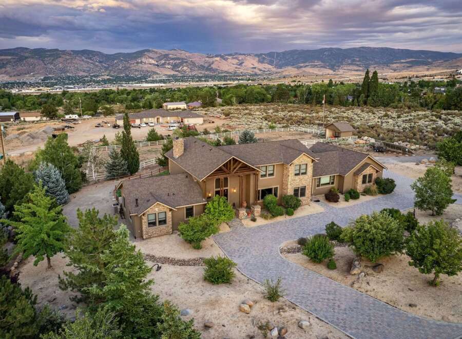 Experience luxury living in this stunning estate, featuring a grand entrance with a covered porch and intricate wooden beams.