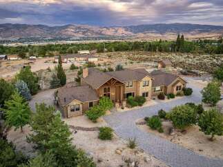 Experience luxury living in this stunning estate, featuring a grand entrance with a covered porch and intricate wooden beams.