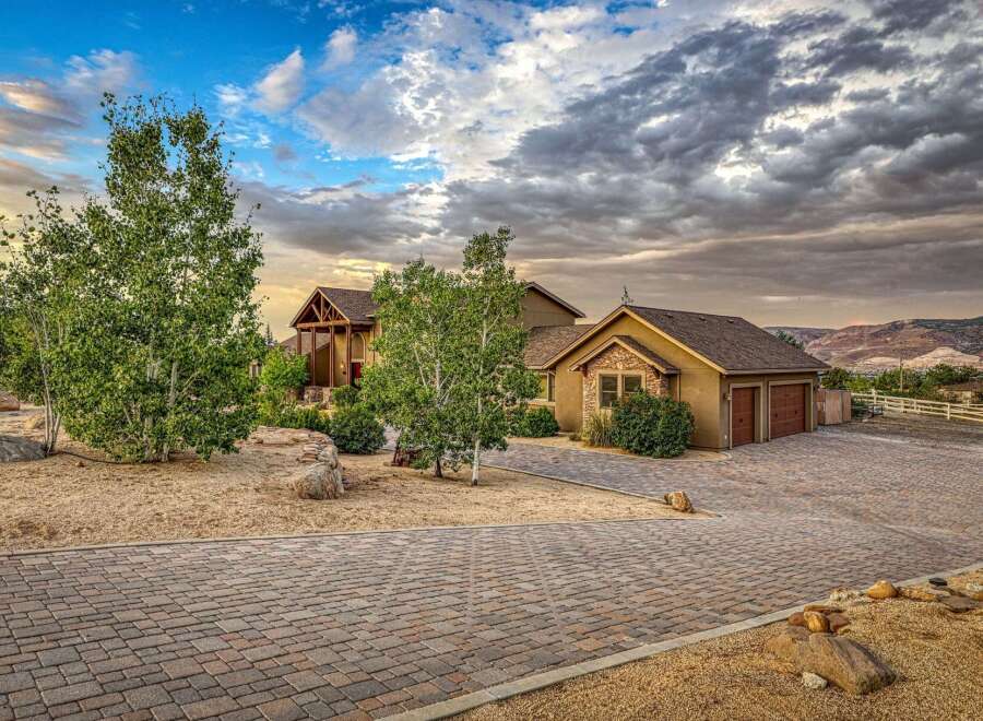 Discover this stunning custom-built home nestled in a picturesque landscape, featuring a grand entrance with a covered porch and rich wood accents.