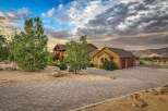 Discover this stunning custom-built home nestled in a picturesque landscape, featuring a grand entrance with a covered porch and rich wood accents.