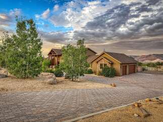 Discover this stunning custom-built home nestled in a picturesque landscape, featuring a grand entrance with a covered porch and rich wood accents.