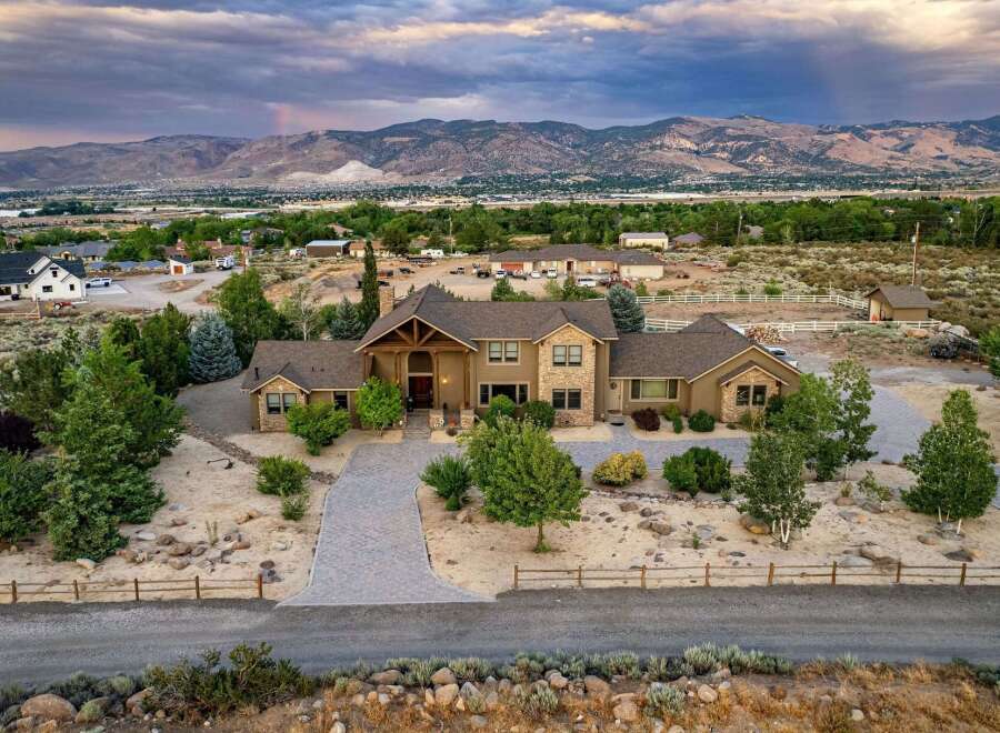 Experience luxury living in this expansive estate, featuring a grand entrance with a wooden-beamed portico and a striking stone facade.