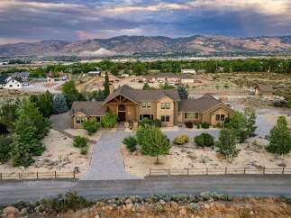 Experience luxury living in this expansive estate, featuring a grand entrance with a wooden-beamed portico and a striking stone facade.