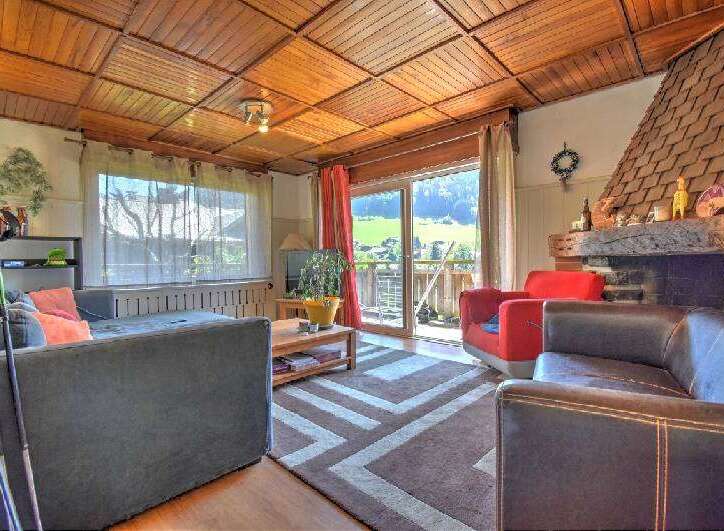 Experience cozy living in this charming living room, featuring a warm wooden ceiling and a rustic stone fireplace.