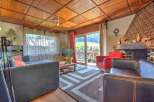 Experience cozy living in this charming living room, featuring a warm wooden ceiling and a rustic stone fireplace.