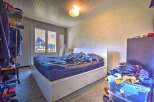 This cozy bedroom features a comfortable bed with a white headboard, perfect for a restful night's sleep.