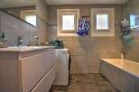 This modern bathroom features a sleek vanity with a built-in sink and ample storage, complemented by a matching washing machine.