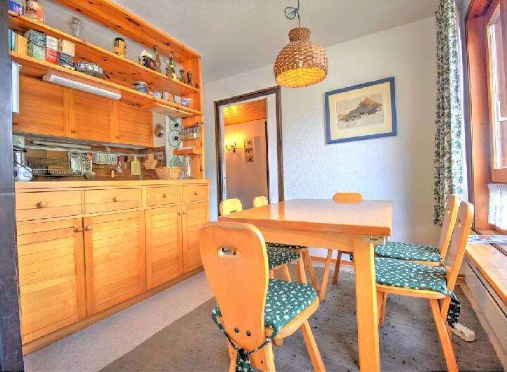Enjoy cozy meals in this charming dining area featuring a warm wooden table and chairs with delightful green patterned cushions.