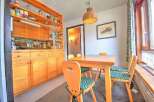 Enjoy cozy meals in this charming dining area featuring a warm wooden table and chairs with delightful green patterned cushions.