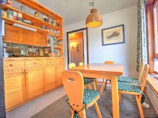 Enjoy cozy meals in this charming dining area featuring a warm wooden table and chairs with delightful green patterned cushions.