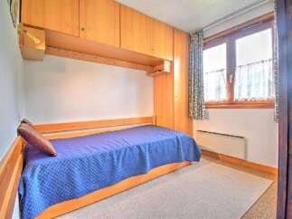 This cozy bedroom features a built-in bed with a vibrant blue comforter, perfect for a restful night's sleep.