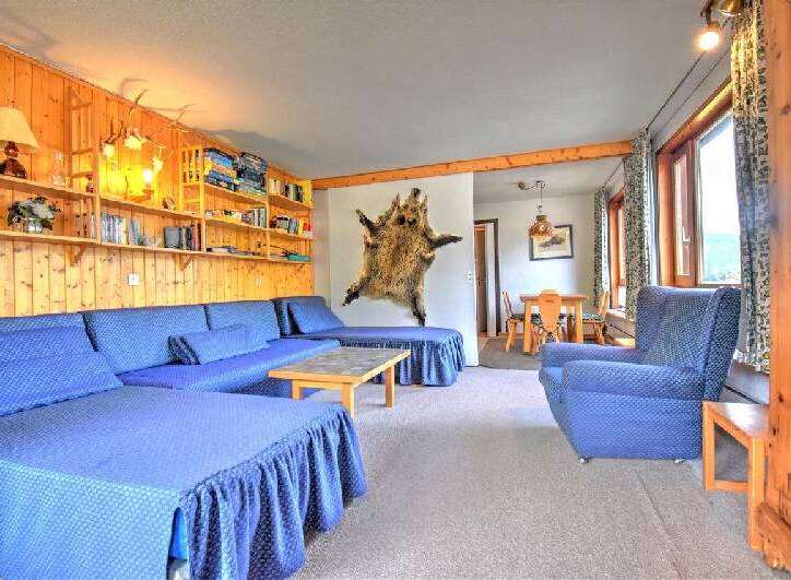 Experience rustic charm in this cozy living area featuring a large, L-shaped blue sectional sofa perfect for gatherings.