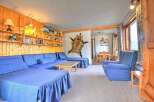 Experience rustic charm in this cozy living area featuring a large, L-shaped blue sectional sofa perfect for gatherings.