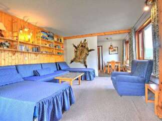 Experience rustic charm in this cozy living area featuring a large, L-shaped blue sectional sofa perfect for gatherings.