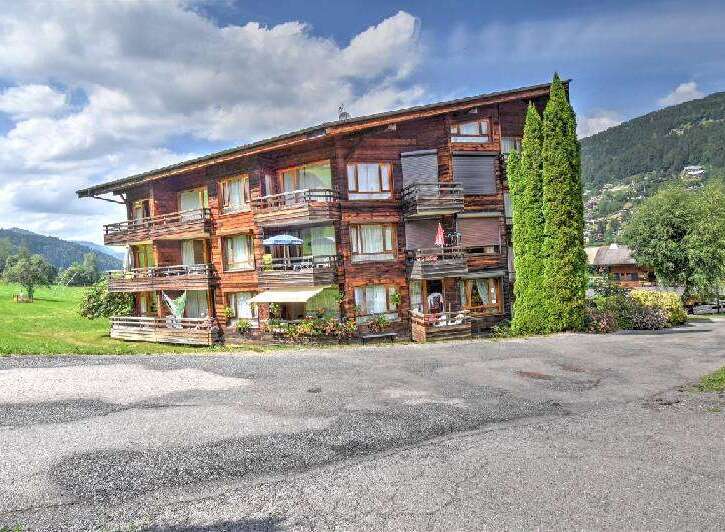 Experience alpine living in this charming wooden apartment building, nestled amidst lush green hills and picturesque mountain scenery.