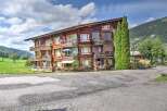 Experience alpine living in this charming wooden apartment building, nestled amidst lush green hills and picturesque mountain scenery.