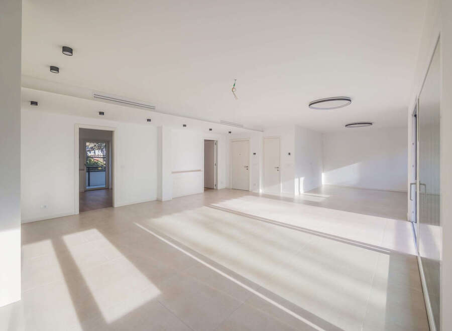 This spacious, modern apartment features an open-concept living area bathed in natural light from large windows.