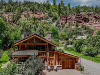 Nestled against a stunning red rock cliff face, this rustic log home offers unparalleled natural beauty and serene living.