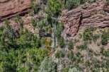 Discover a unique property featuring a stunning natural waterfall cascading down red rock cliffs.