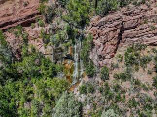Discover a unique property featuring a stunning natural waterfall cascading down red rock cliffs.