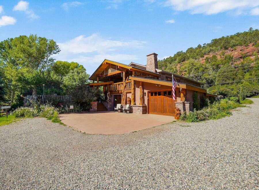 Experience rustic luxury in this stunning mountain home, featuring a grand wooden exterior and a prominent stone chimney.