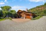 Experience rustic luxury in this stunning mountain home, featuring a grand wooden exterior and a prominent stone chimney.