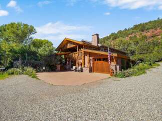 Experience rustic luxury in this stunning mountain home, featuring a grand wooden exterior and a prominent stone chimney.