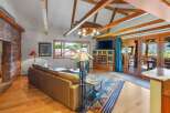 Experience rustic charm in this spacious living area featuring a soaring vaulted ceiling with exposed wooden beams and a unique wagon wheel chandelier.