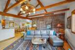 Experience rustic charm in this spacious living area, featuring a grand stone fireplace and exposed wooden beams that add warmth and character.