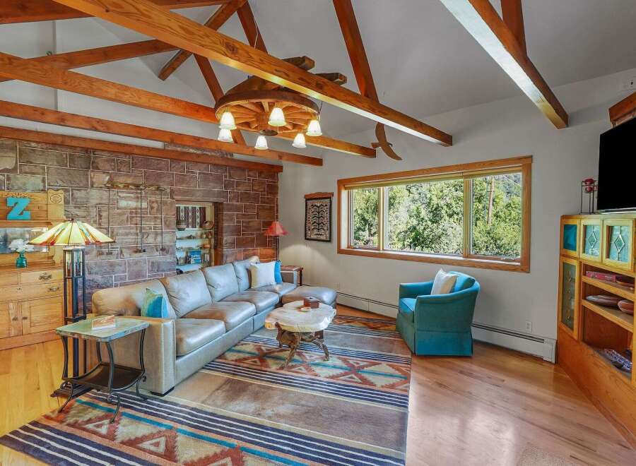 Experience rustic charm in this spacious living room, featuring a striking stone accent wall and exposed wooden beams that add warmth and character.