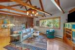 Experience rustic charm in this spacious living room, featuring a striking stone accent wall and exposed wooden beams that add warmth and character.