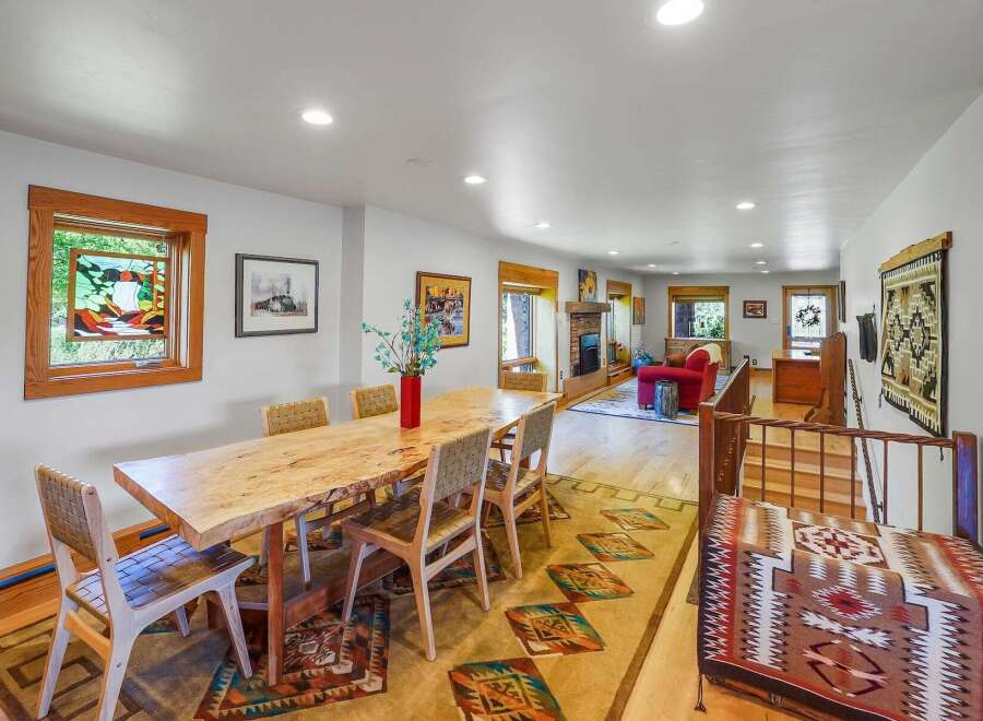 Experience rustic charm in this spacious dining and living area, featuring a live-edge dining table perfect for gatherings and a cozy fireplace in the adjacent living room.