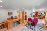This spacious open-concept living area features a dedicated home office space with a large wooden desk and comfortable office chair.