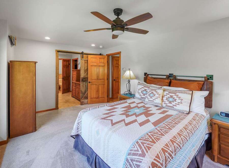 Experience rustic charm in this inviting bedroom, featuring a cozy bed adorned with a Southwestern-inspired quilt and decorative pillows.