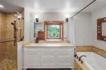 This spacious bathroom features a large vanity with ample storage and a bright window overlooking lush greenery.
