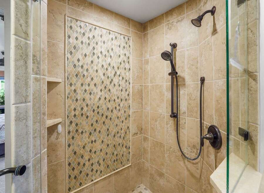 Experience luxury in this beautifully tiled shower featuring a decorative mosaic accent wall and dual shower heads for a spa-like experience.